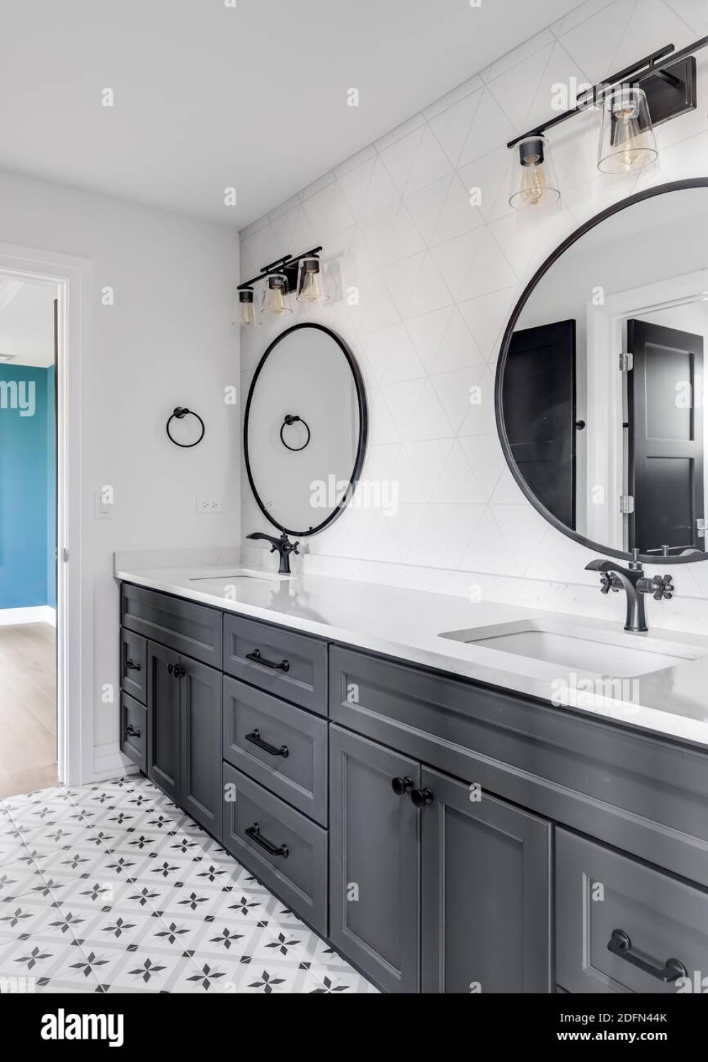A beautiful bathroom with a dark grey vanity, circular mirrors